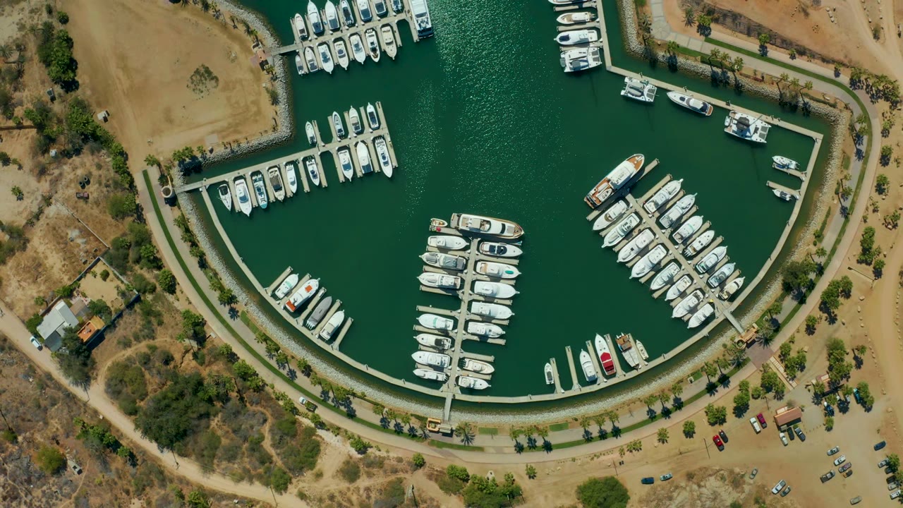 Aerial view of boats tied to docks inside a curved marina basin.
