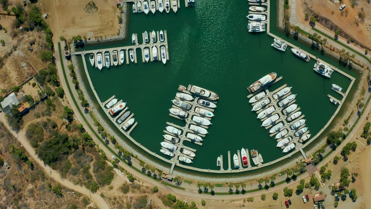 Top-down marina view with boat rows, docks, road, and dry shoreline land.