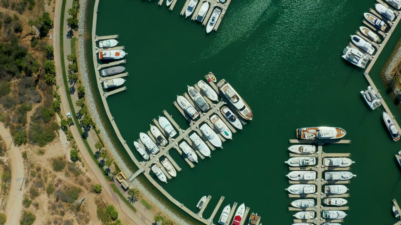 Aerial marina view with a boat moving near docked yachts.