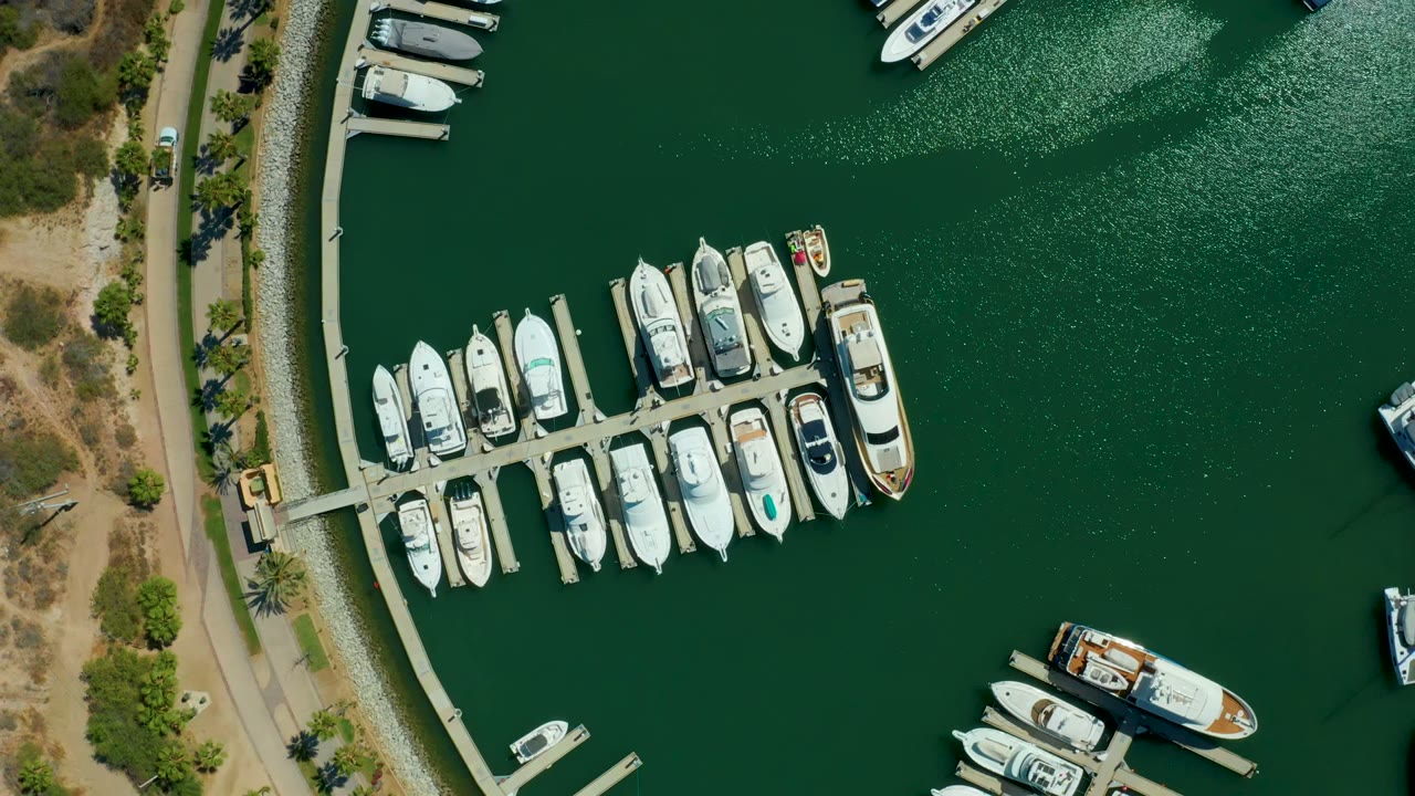 Aerial view of boats at a marina dock with open green water to the right.