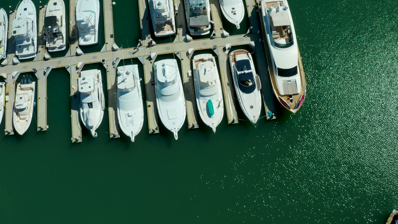 Docked yachts and empty green water viewed from above.