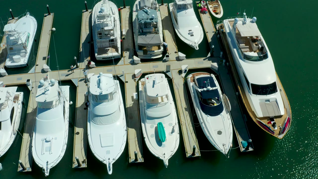 Aerial view of clustered yachts and dock walkways over calm green water.