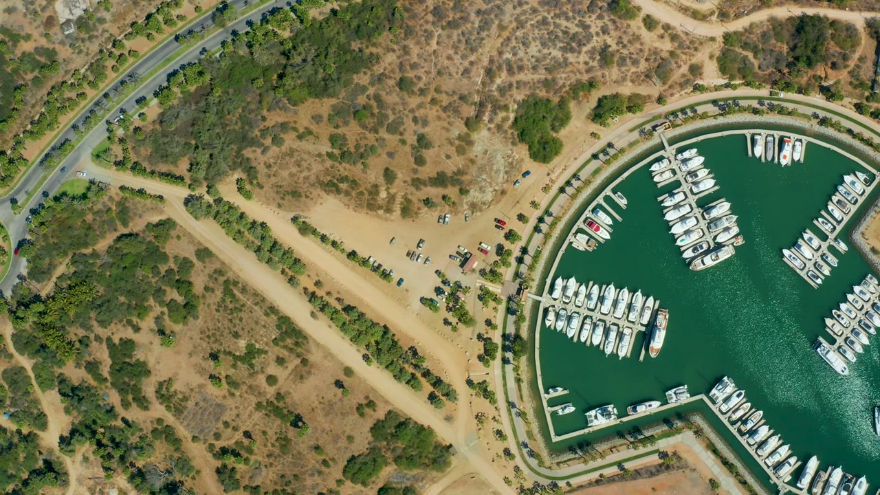 Aerial view of marina docks and adjacent sandy parking area.