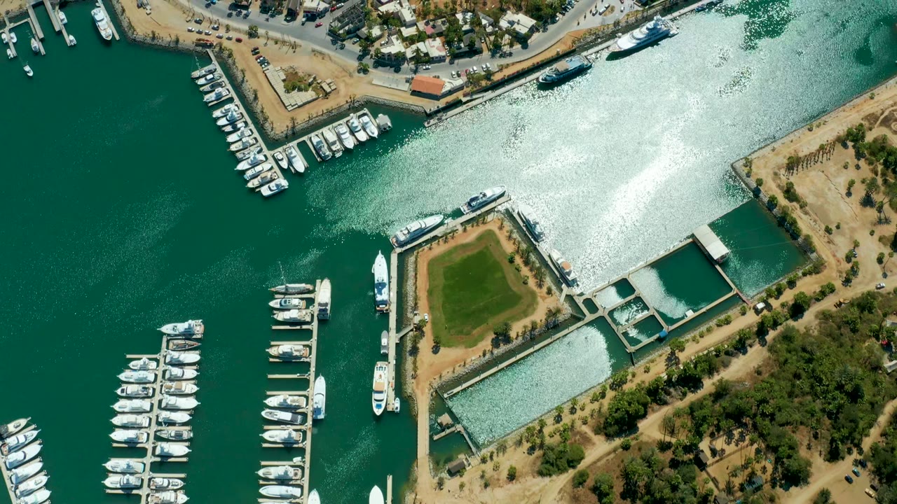 Top-down marina view with boats at docks and a bright water channel.