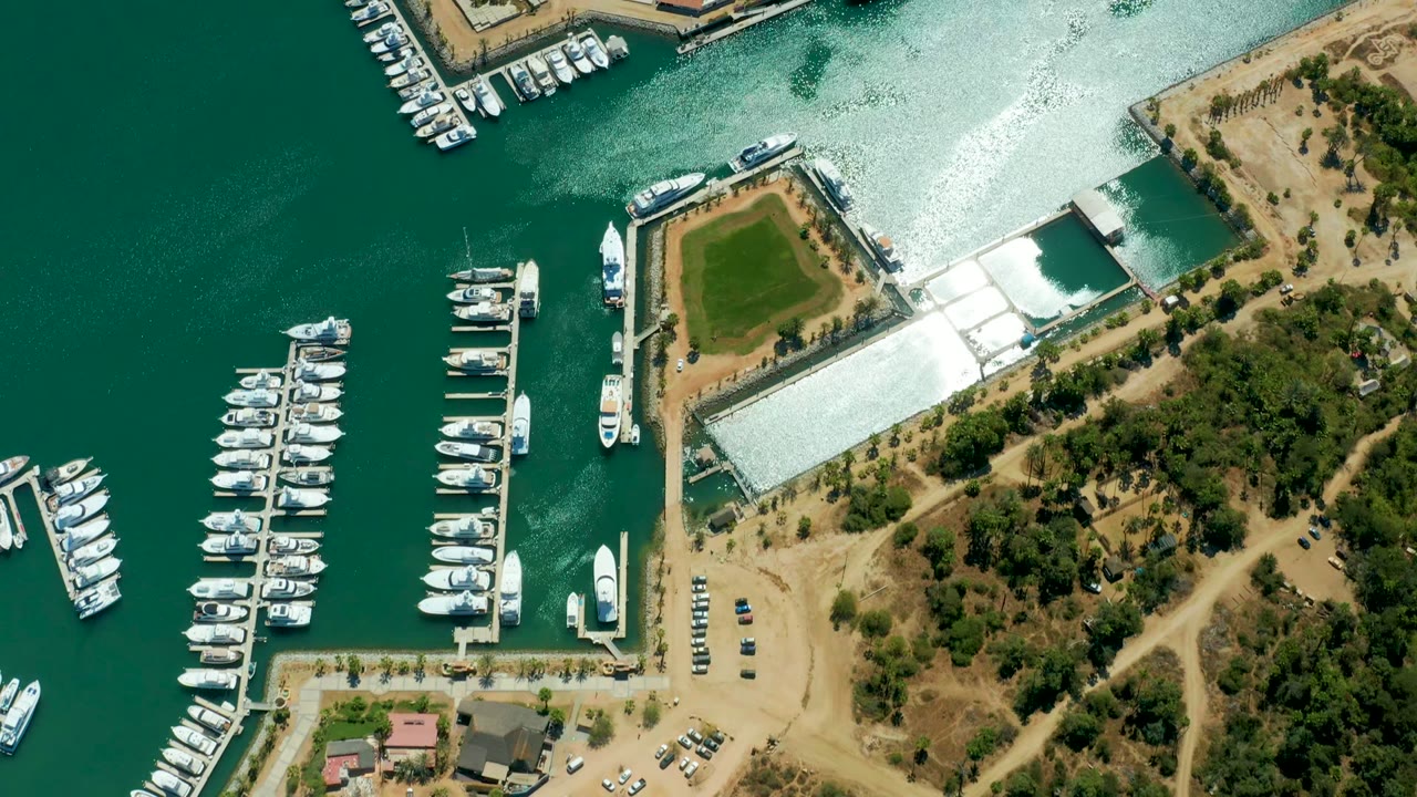Aerial marina view with rows of docked boats and bright water glare.