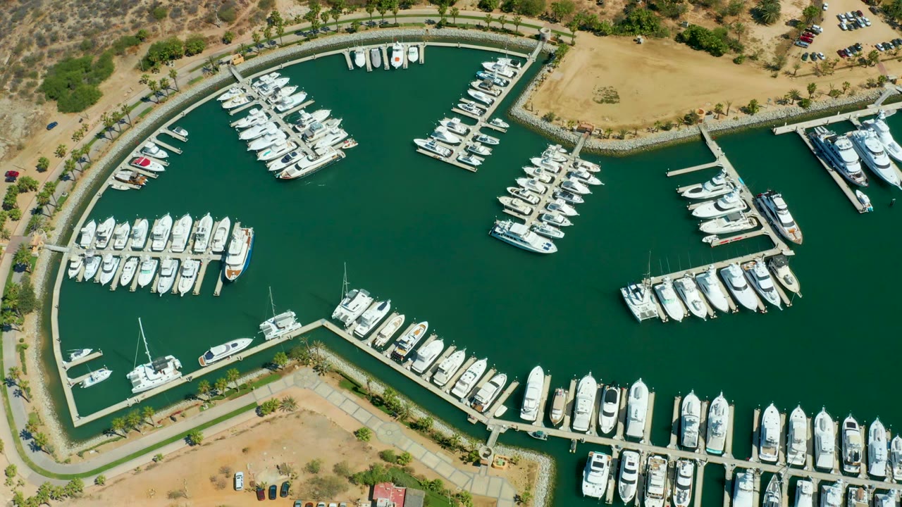 Aerial marina basin with docked boats and tan land at the edges.