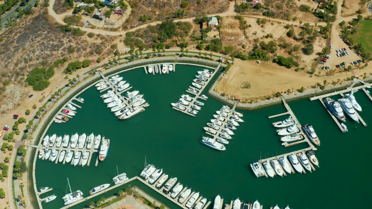 Overhead marina view with boats moored along docks and dry land around the harbor.