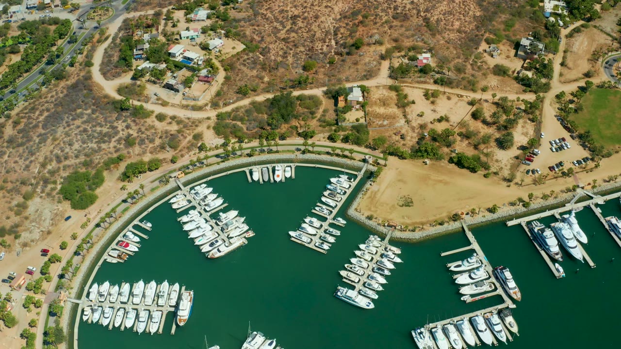 Aerial marina view with boats lined along docks and arid terrain beyond.