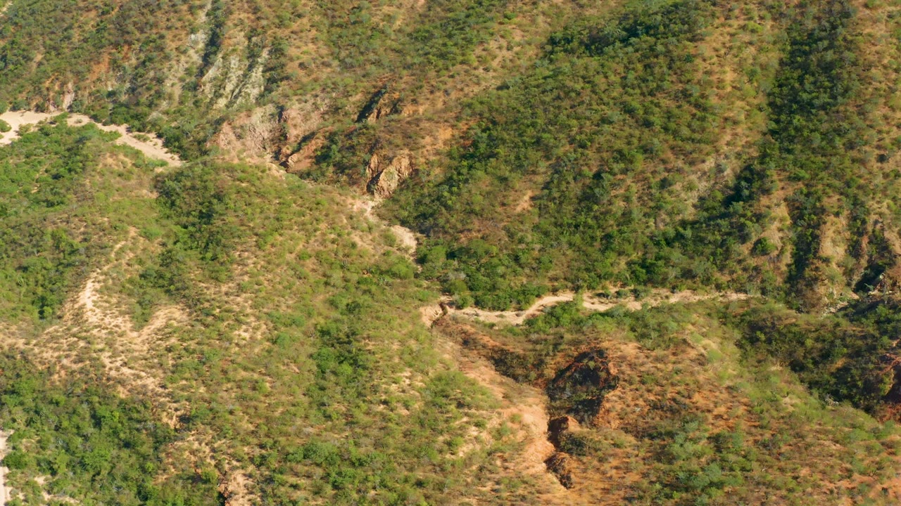 Winding road and rocky hillside gullies viewed from above.