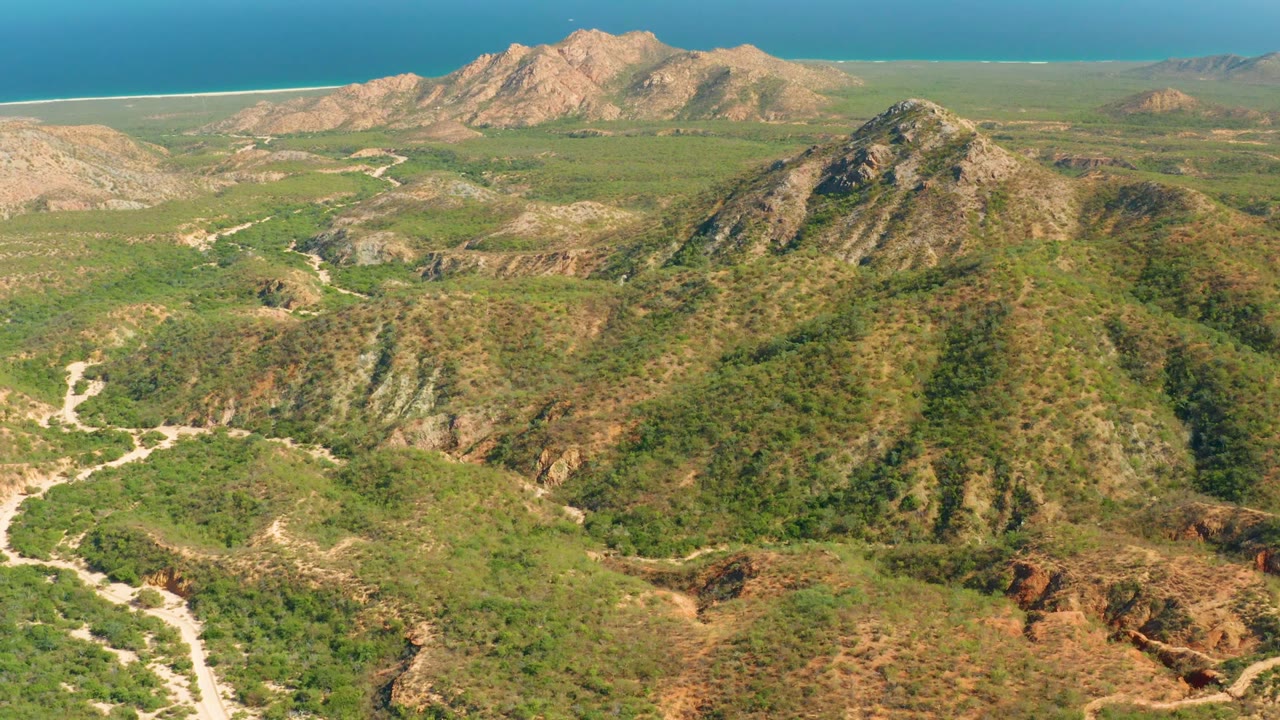 At 0:02, El Salado Viejo's rugged hills and patchy scrub stretch toward the sandy coastline, with multiple dirt tracks visible across the valley and no visible people.
