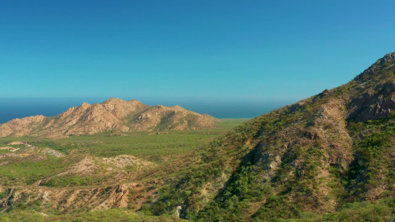 Aerial mountain valley with a steep rocky slope at the right edge