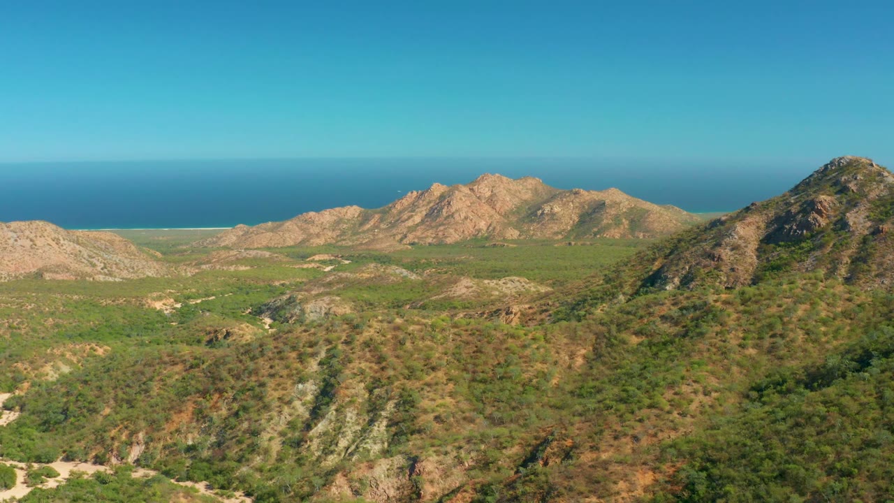 Rocky coastal hills under clear sky with ocean in background