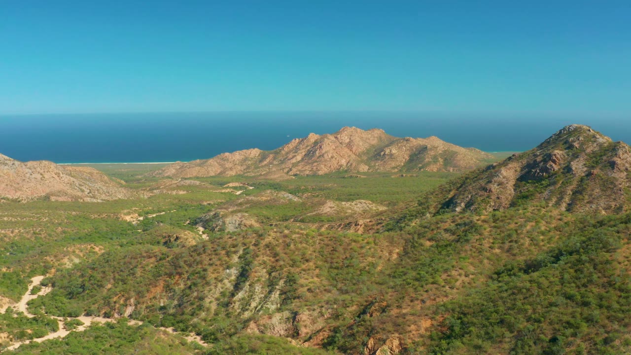 Coastal mountain landscape with green vegetation and blue ocean behind