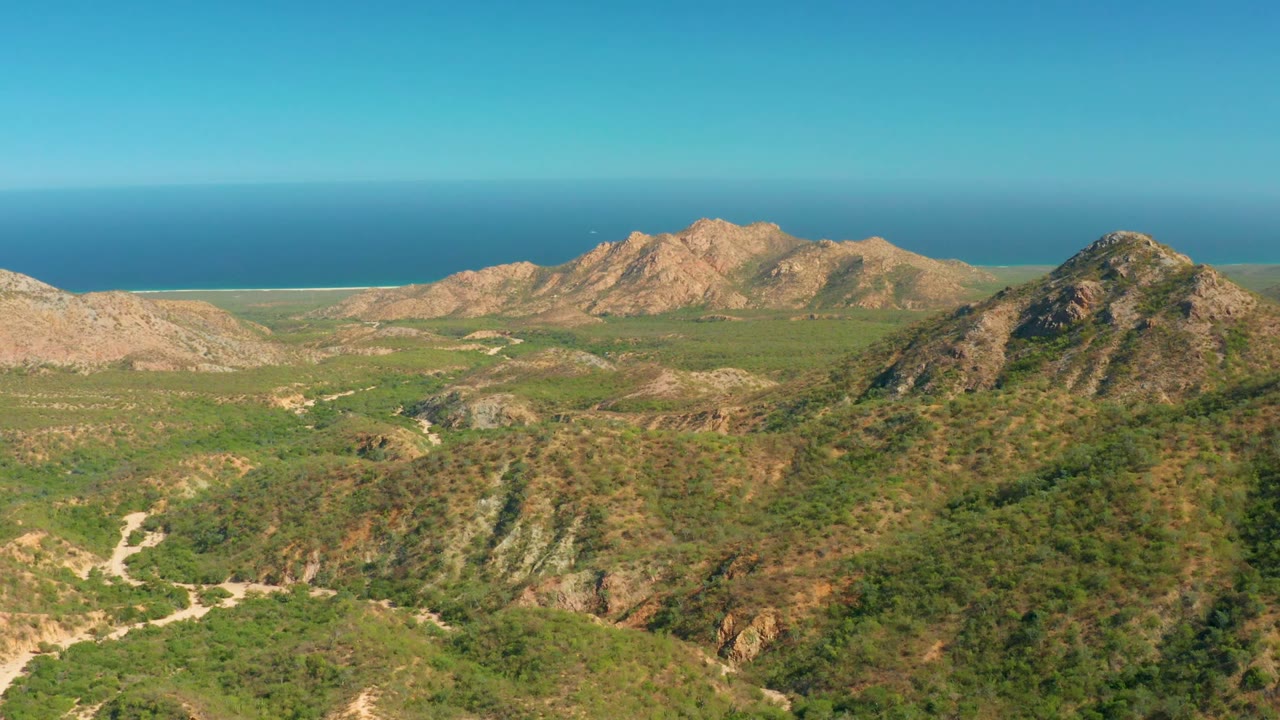 Rocky green hills and distant ocean under a clear sky
