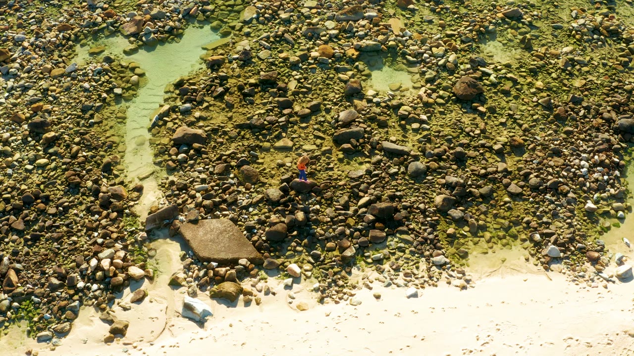 Person crossing a rocky shallow stream seen from above