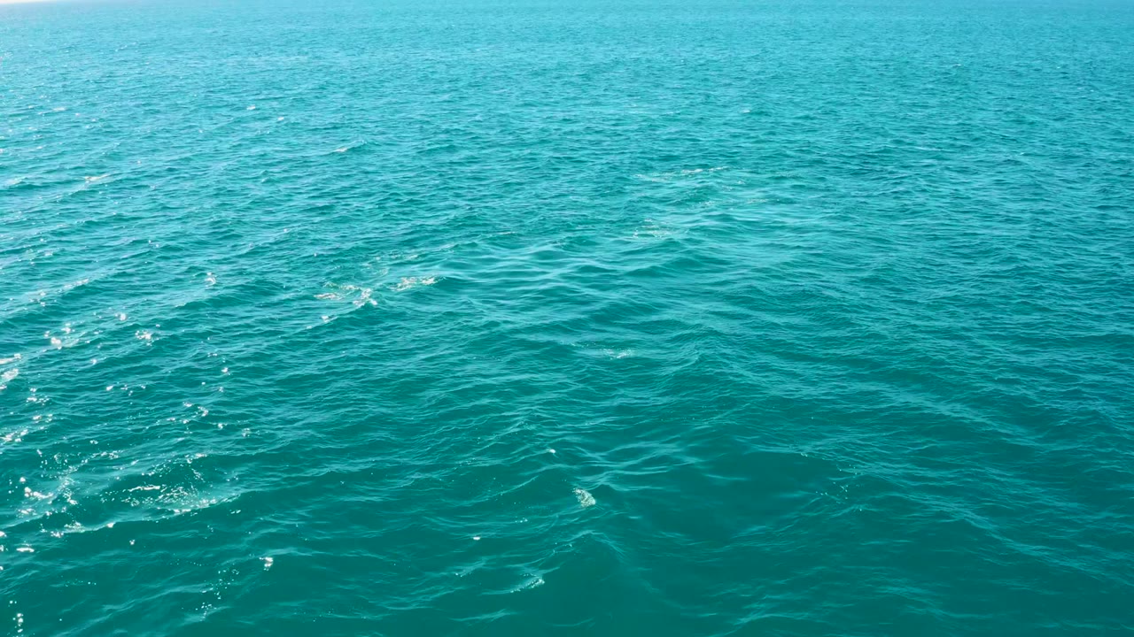 Open turquoise water with low ripples and scattered foam