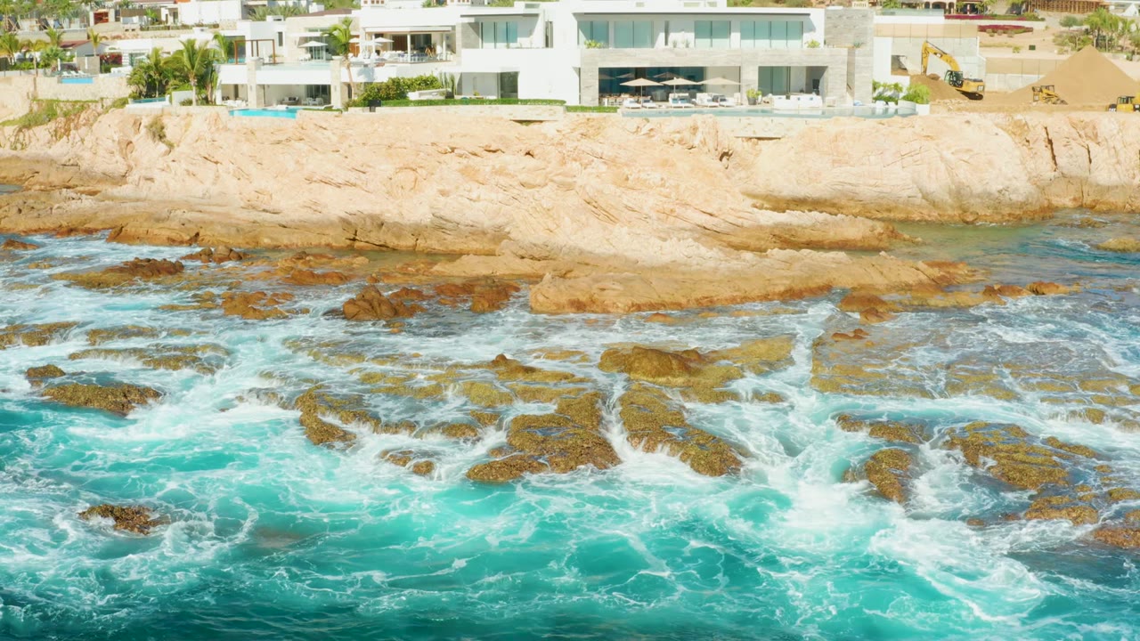 White cliffside buildings above waves and rocky shoreline.