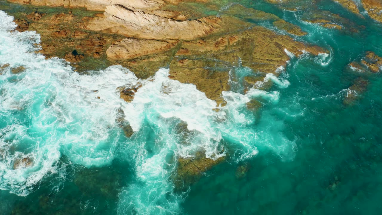 White foam curling around rocks in turquoise water