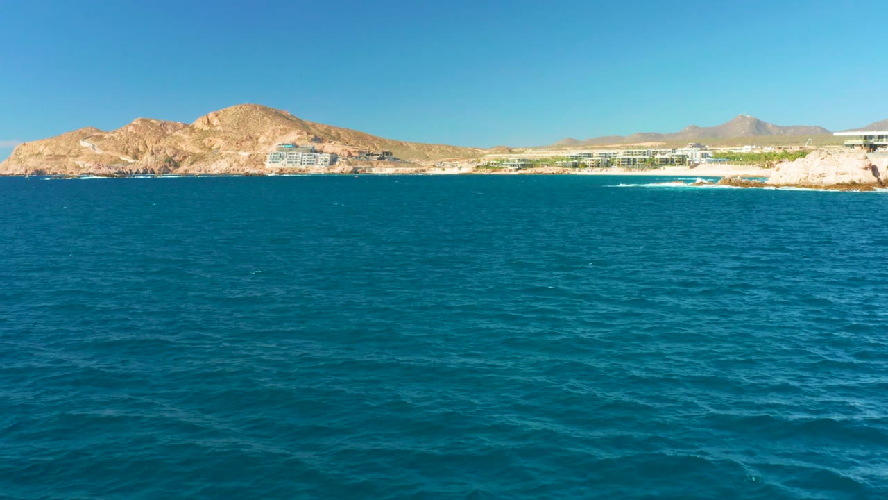 Ocean surface with rocky hills and coastal buildings across the horizon