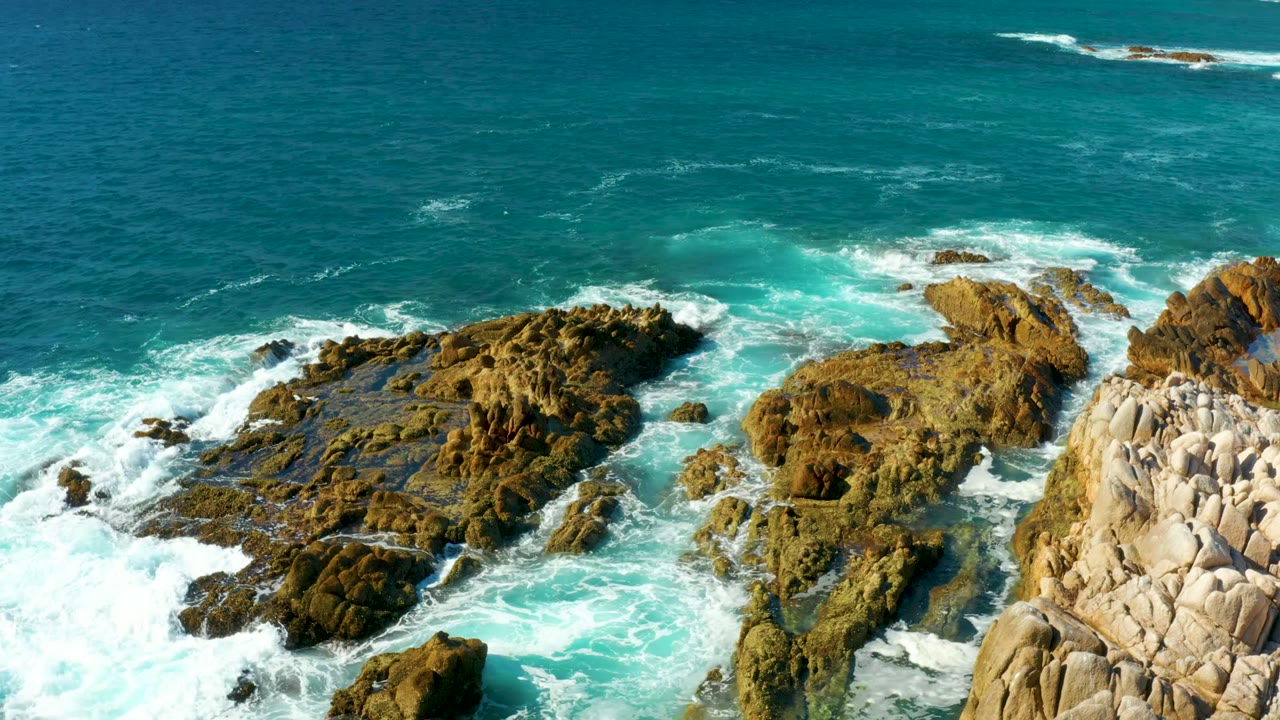 White foam spreading across rocky shoreline