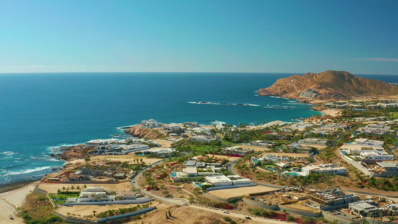 Elevated coastal neighborhood view with ocean horizon and hillside beyond.