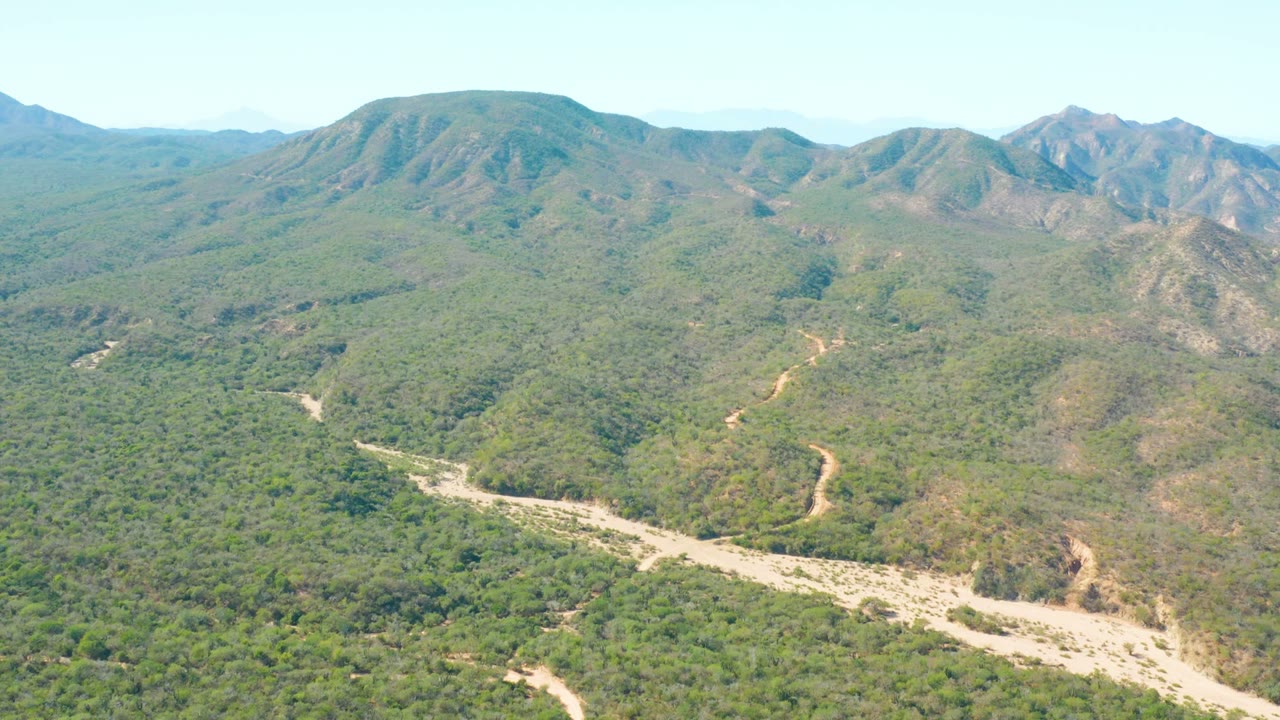 Aerial valley view with dry riverbed below green hills