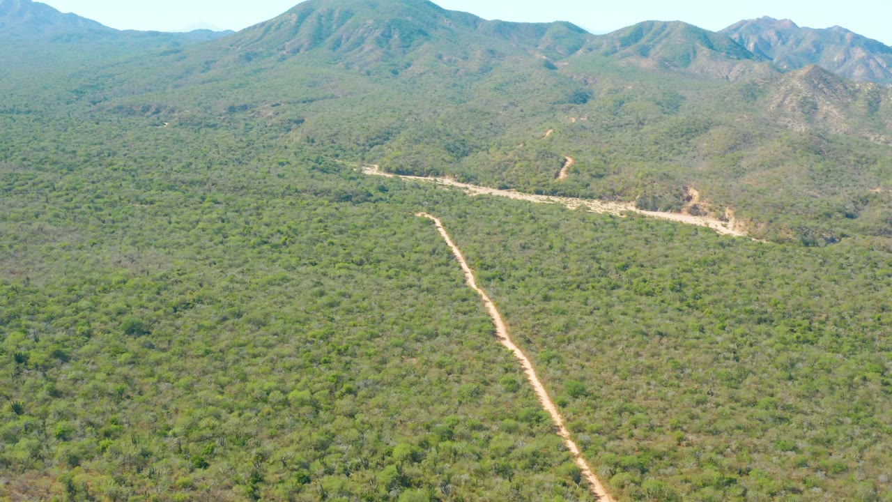 Dirt road and green hillside landscape seen from above.