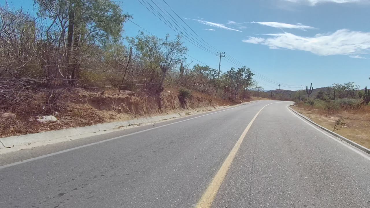 Paved road bending right beside eroded dry roadside bank