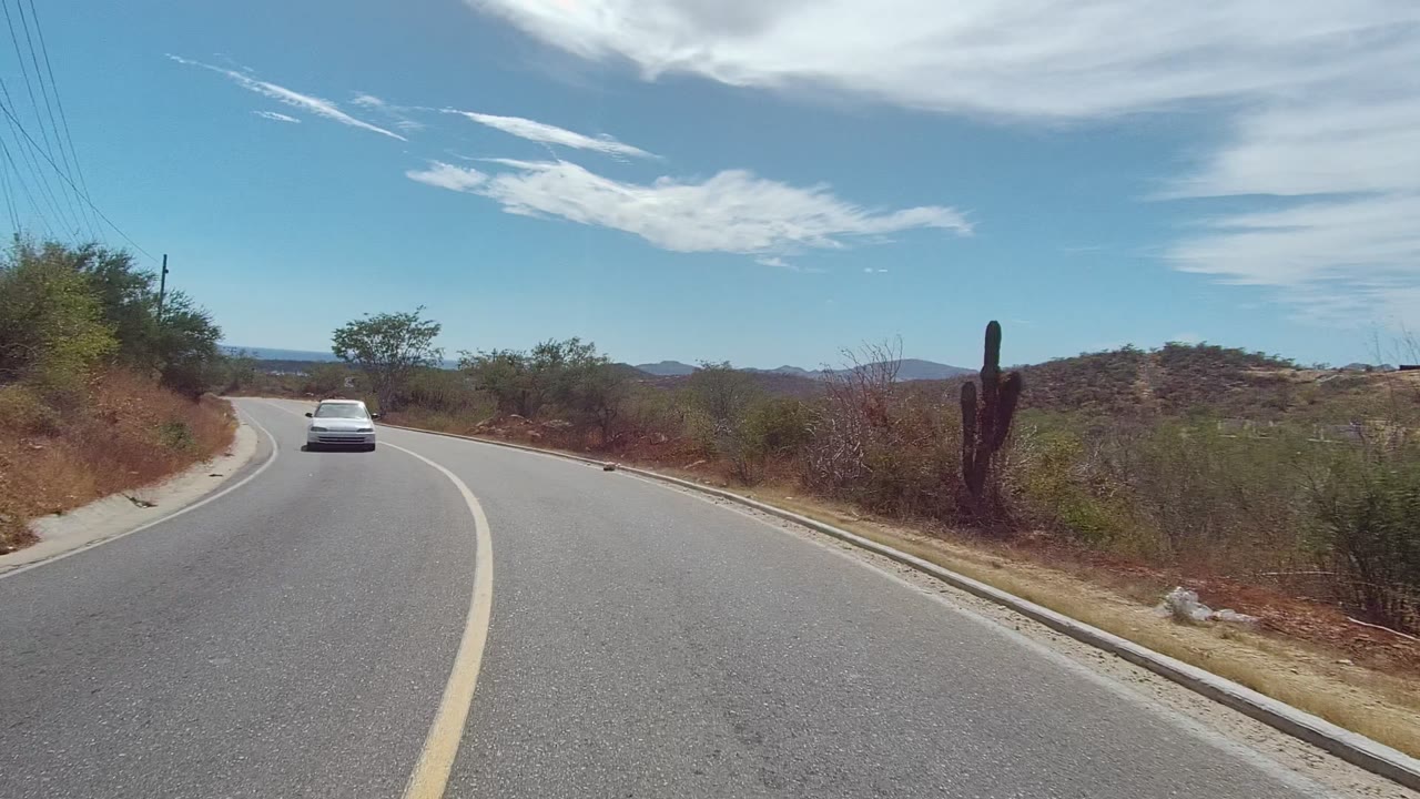 White car on winding road through dry brush