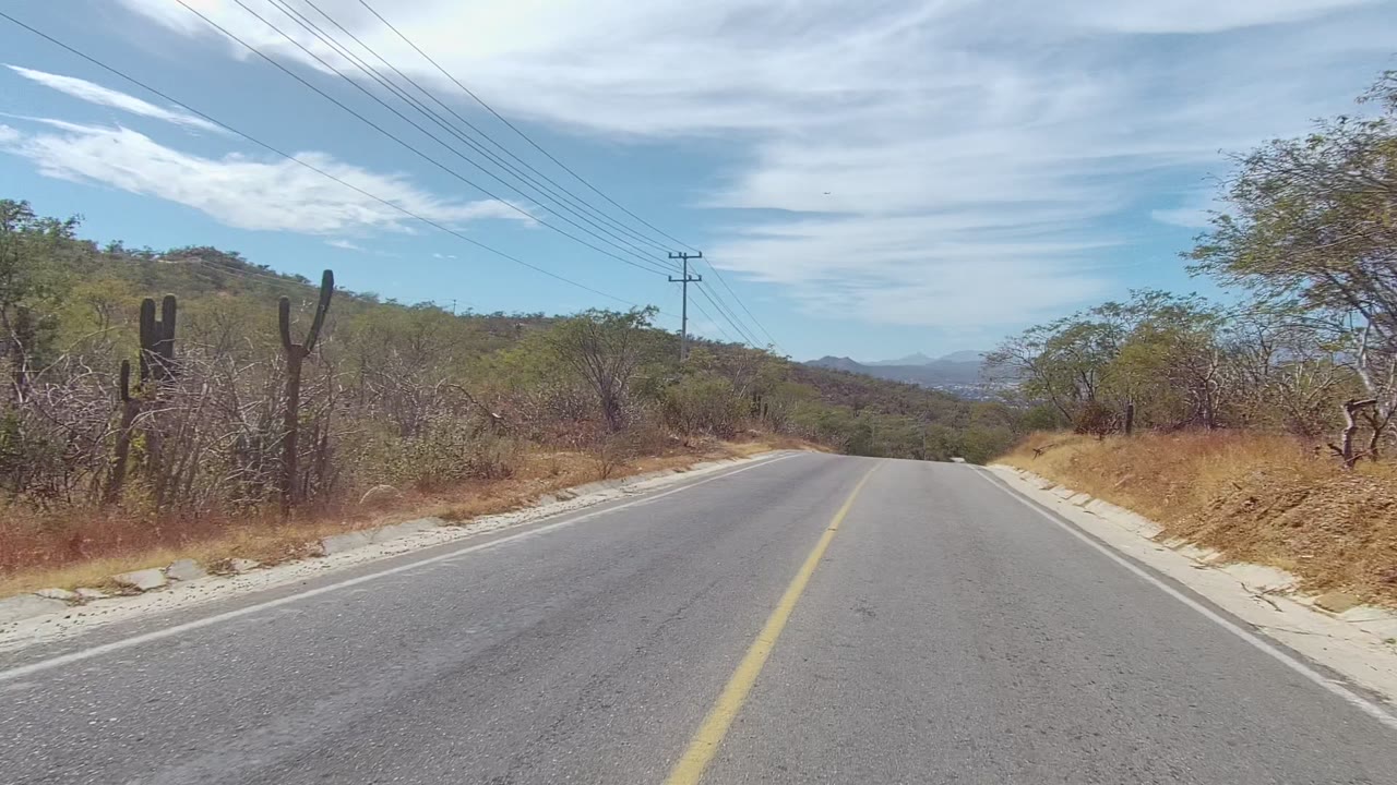 Forward road view with brushy hillside and utility lines