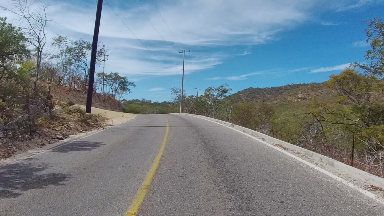 Road crest ahead with scrub and utility poles