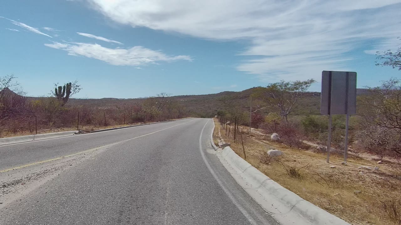 Road beginning to straighten with dry brush and hills ahead