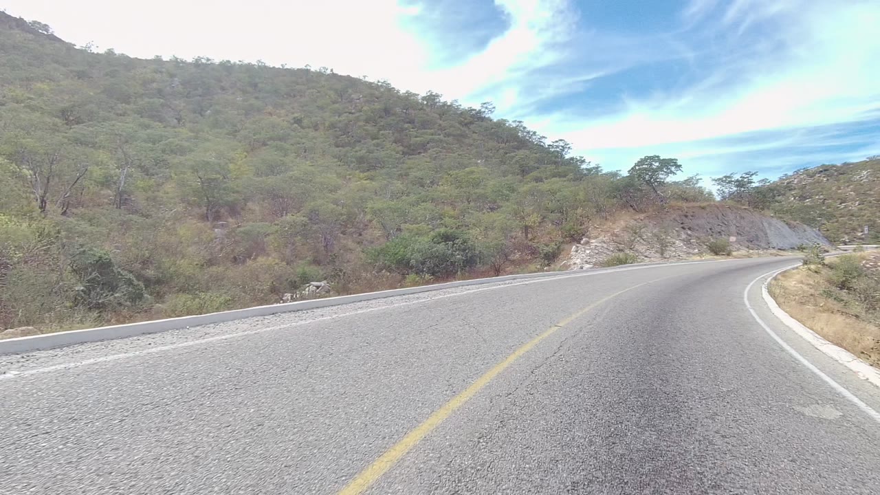 Road curve with guard edge and dry hillside vegetation