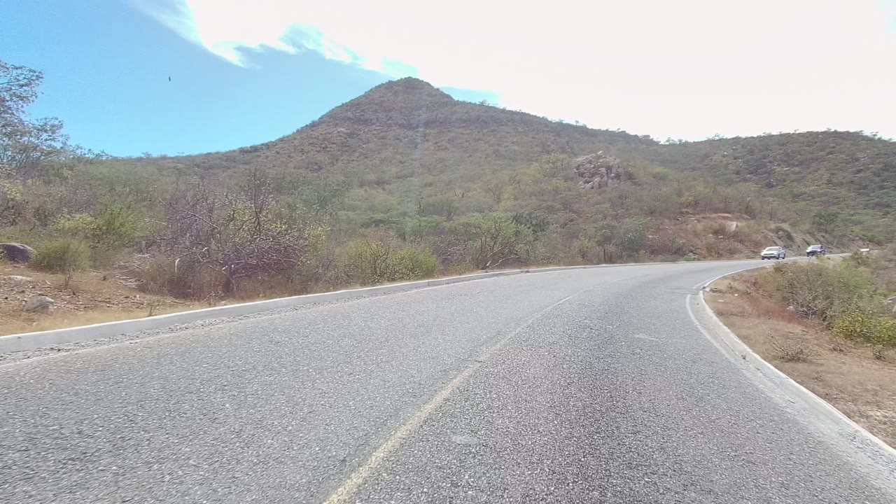 Winding road with small distant cars near the curve.
