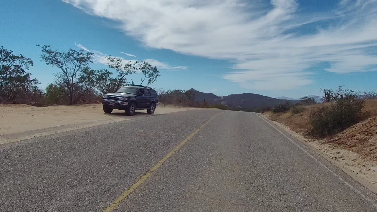 Black SUV passing near the camera on a desert road