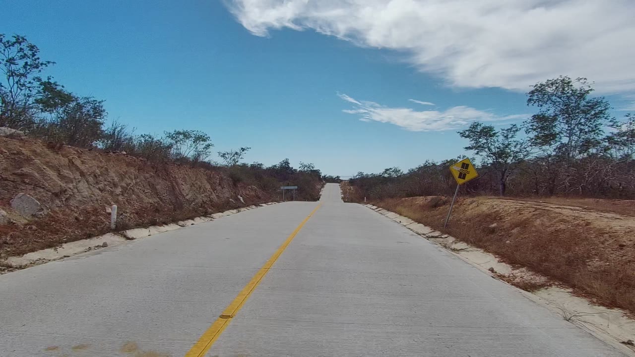 Desert road approaching a yellow warning sign