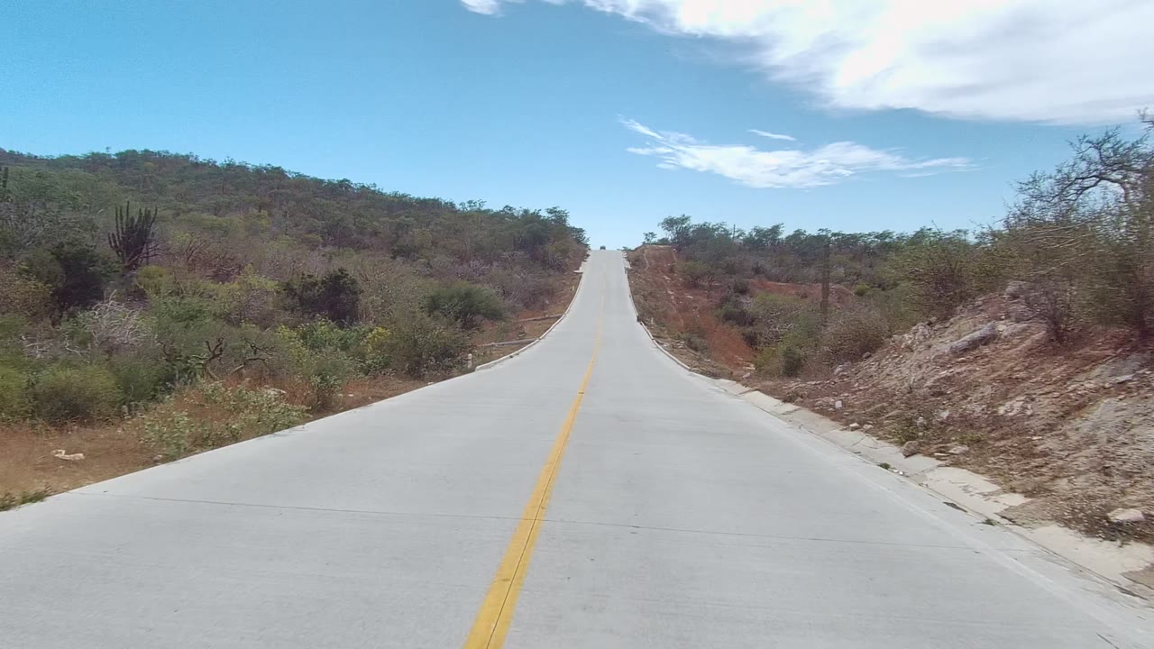 Concrete road bordered by rocky slope and desert brush