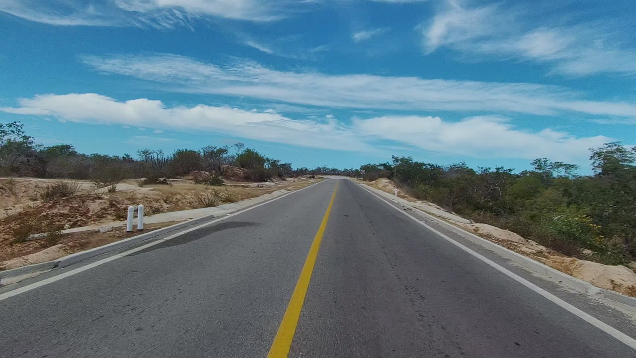 Roadside kilometer marker beside straight road in arid terrain