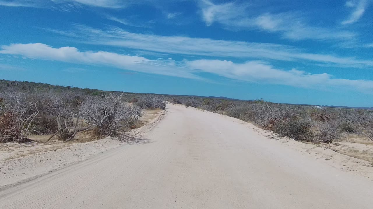Empty sandy road with scrub and distant hills