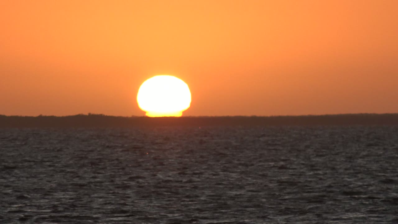 Bright sunset sun above rippled ocean water