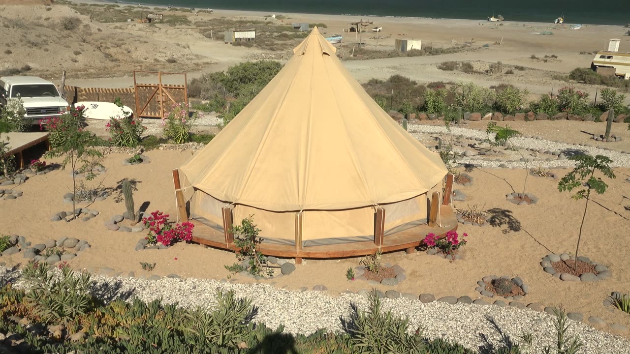 Round desert tent with red flowers and parked vehicles behind it