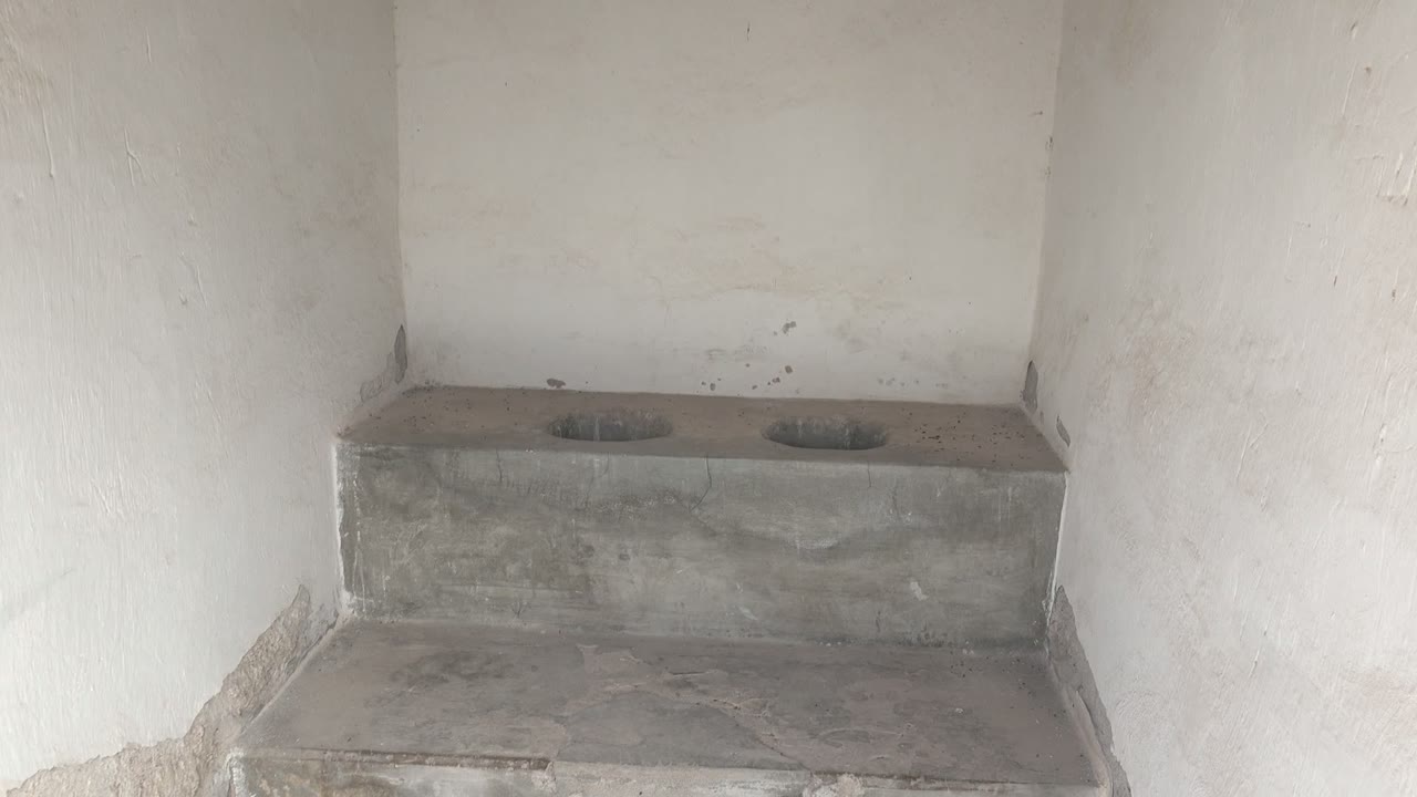 Raised concrete platform with two round openings and white plaster walls.