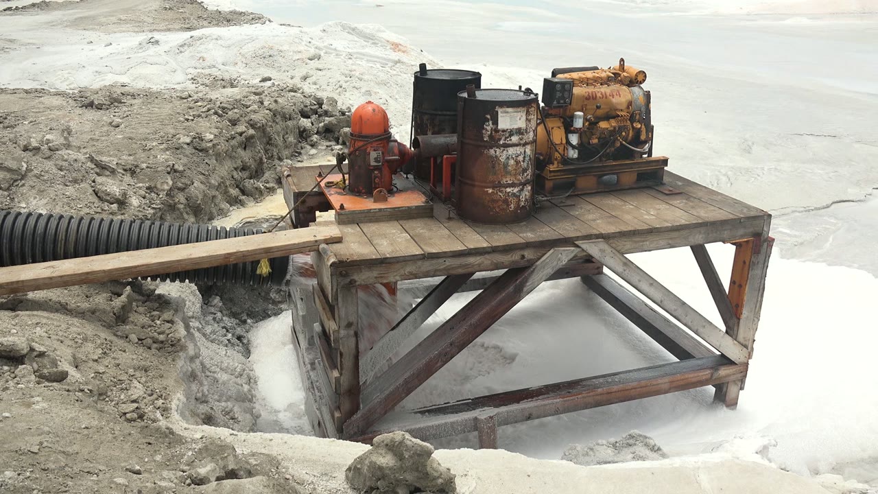 At 0:02, the wooden deck and angled metal supports are clear beneath the rusted pump machinery, with pale ice filling the lower right of the Guerrero Negro frame and no visible people.