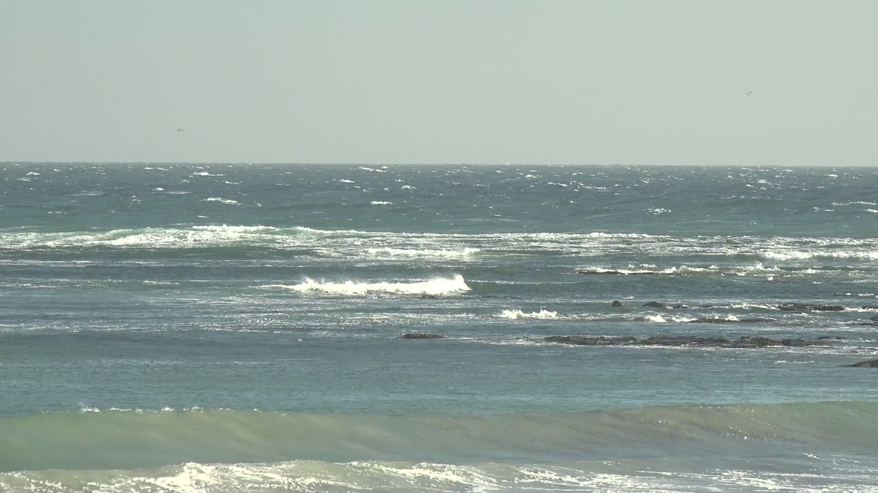 Wind-ruffled ocean off La Bocana fills the frame as parallel wave lines break into white foam across the midground, with no visible people.