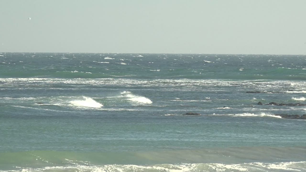 Ocean waves breaking across scattered rocks