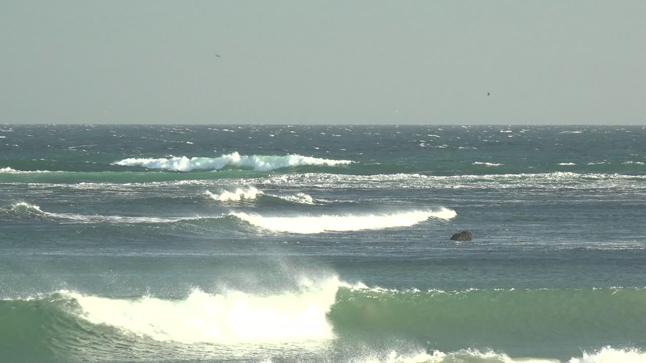 Wide La Bocana ocean view with layered blue-green breakers, white foam bands, a high horizon, and no visible people.