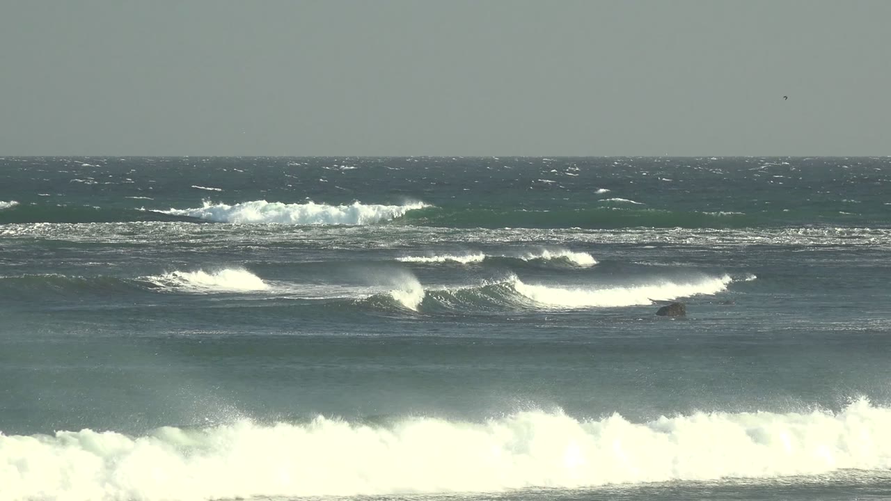Wide La Bocana ocean frame with staggered surf bands, blown white foam on several crests, and no visible people.