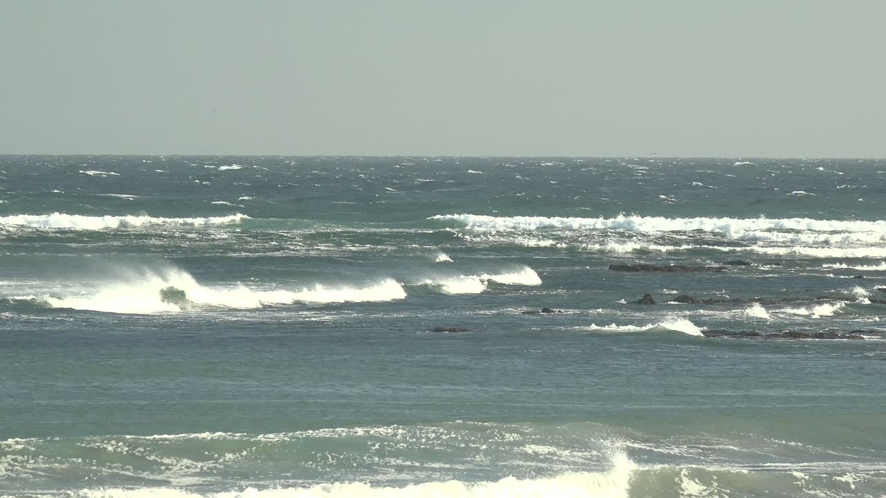 Breaking ocean waves rolling across rocks