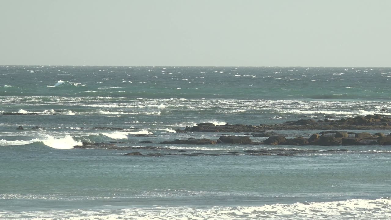 White surf spreading across dark coastal rocks.