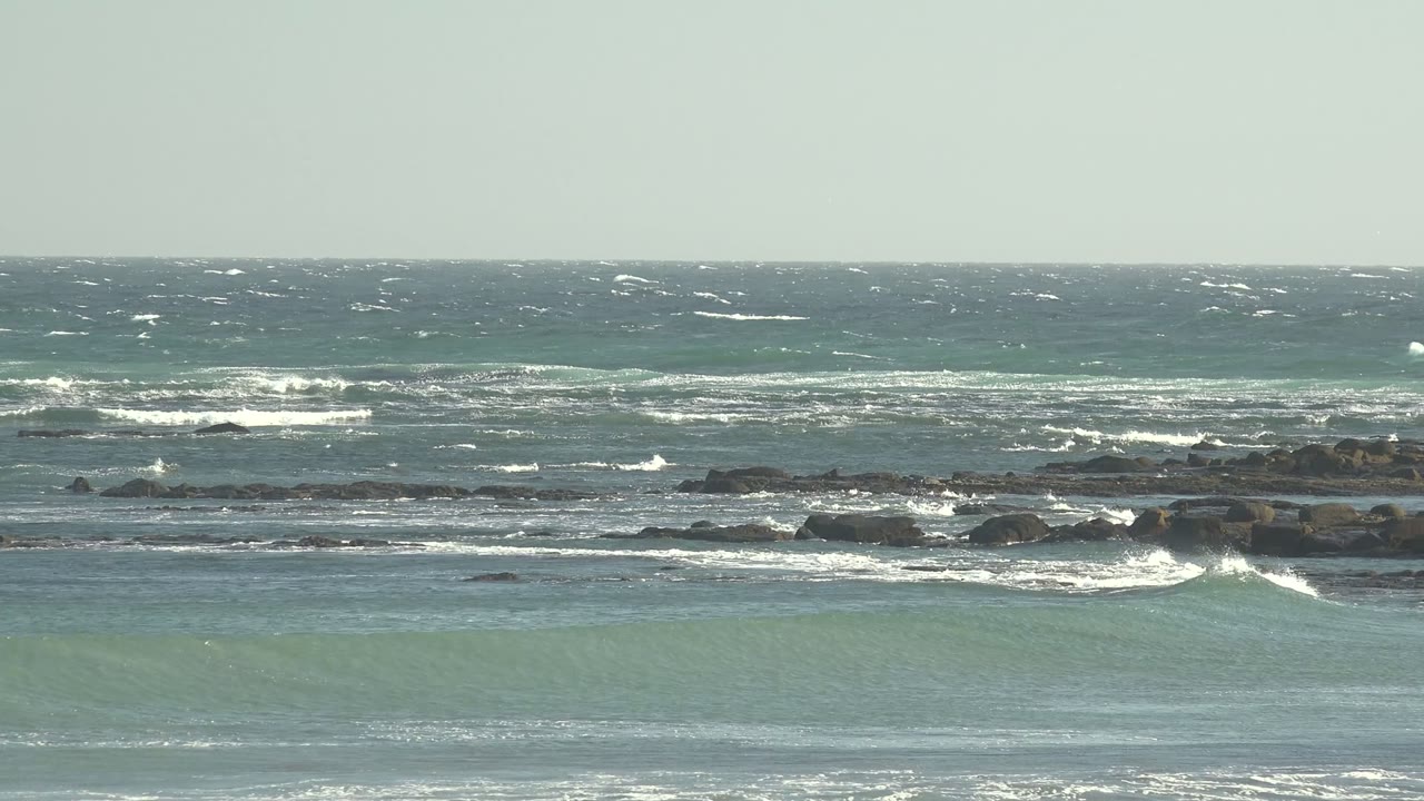 Blue-green surf rolling toward a rocky shoreline